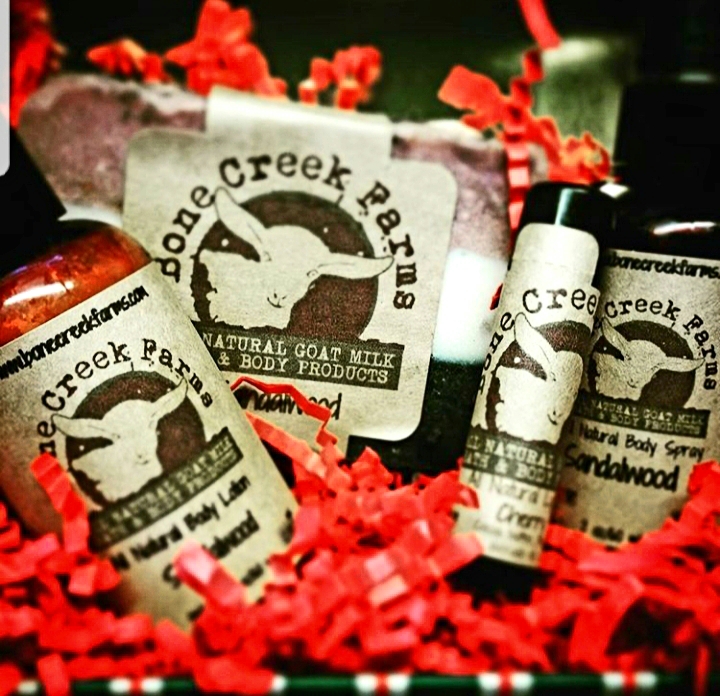 Tisha+Carr+-+20181213_115517 Natural goat milk body products from Bone Creek Farms, including a bar of soap, body lotion, and body spray, arranged in a decorative basket with red crinkle paper.