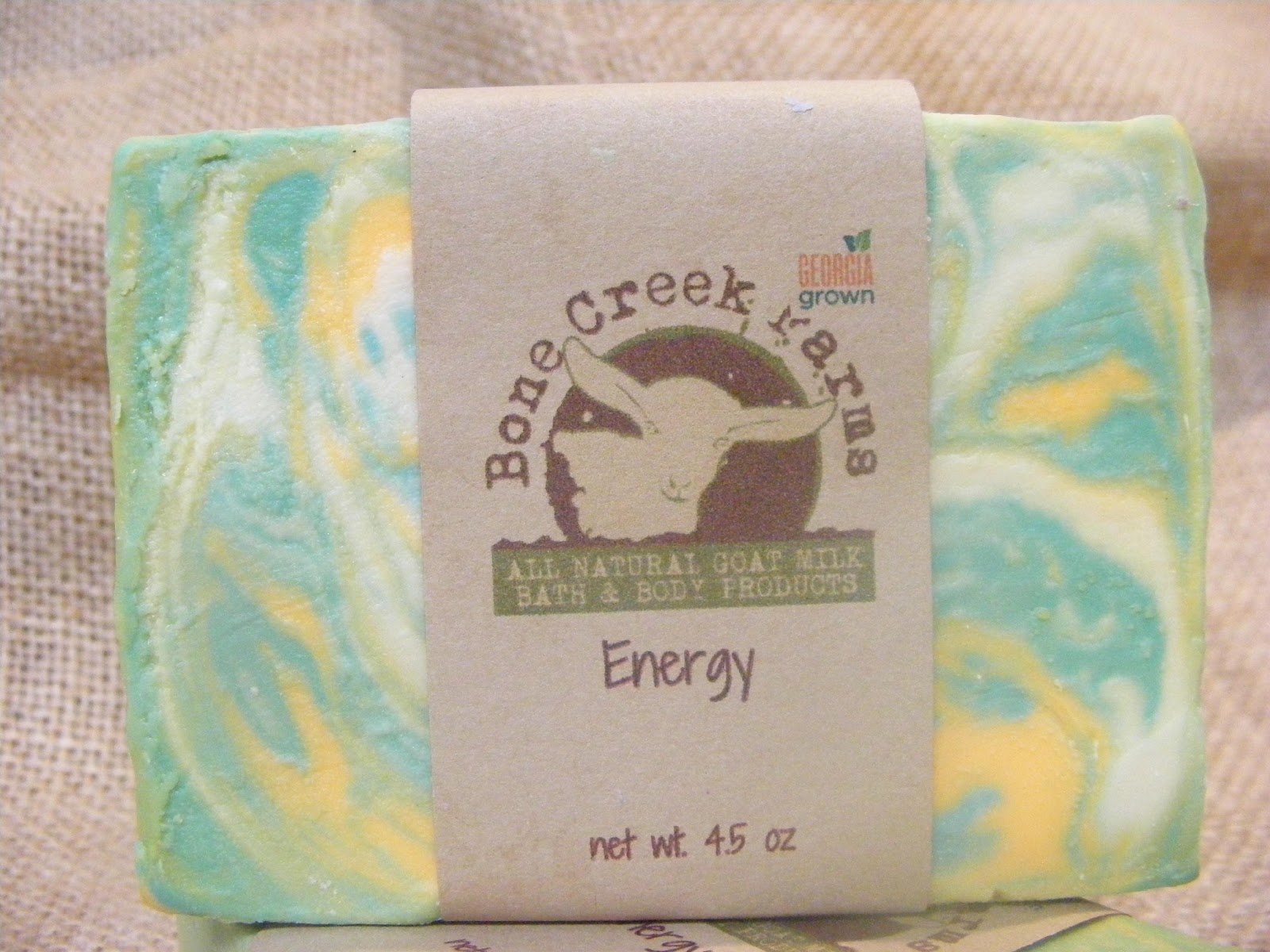energy Natural goat milk soap from Bone Creek Farms, featuring vibrant swirls of blue and yellow, labeled "Energy," weighing 4.5 oz. Ideal for revitalizing baths and body care.