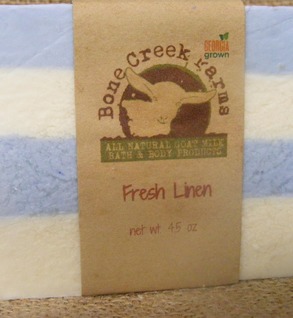 All-natural goat milk soap bar from Bone Creek Farms, featuring a Fresh Linen scent. The soap is presented in a striped design with blue and white colors, and the label indicates a net weight of 4.5 ounces. Ideal for bath and body care enthusiasts seeking organic products.